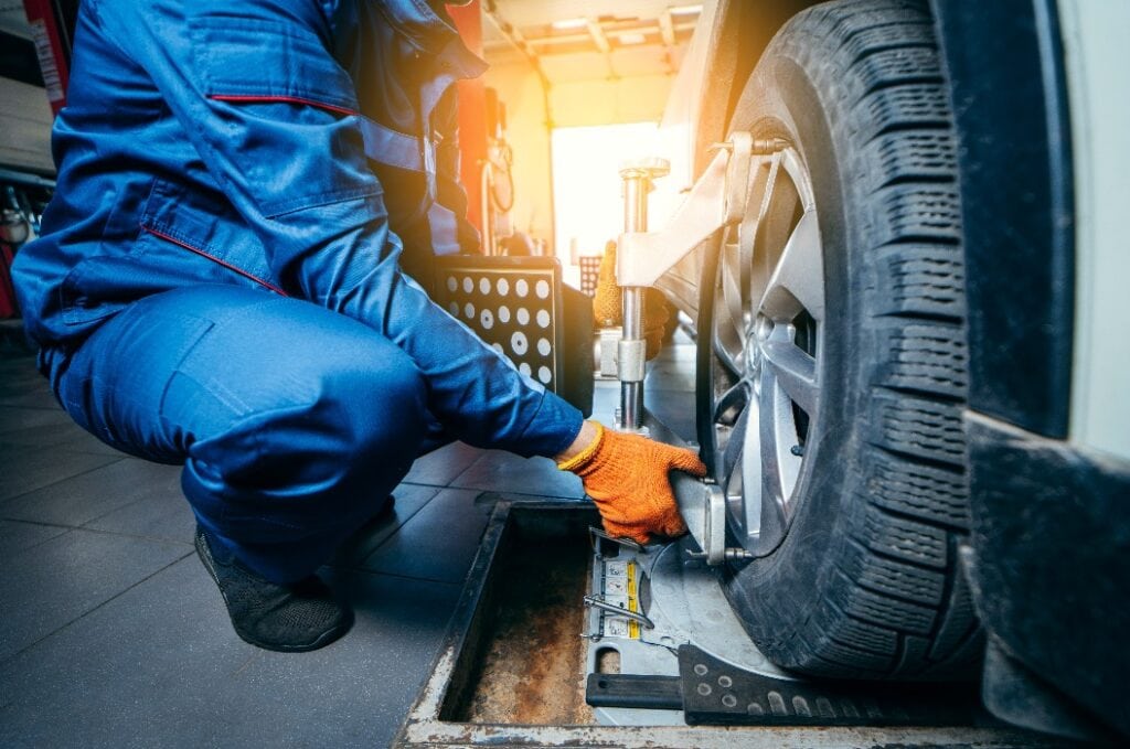 Auto mechanic installing sensor during suspension adjustment and automobile wheel alignment work at repair service station. Close up